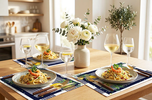 Dining table set with pasta dishes, wine glasses, and a vase of flowers in a kitchen.