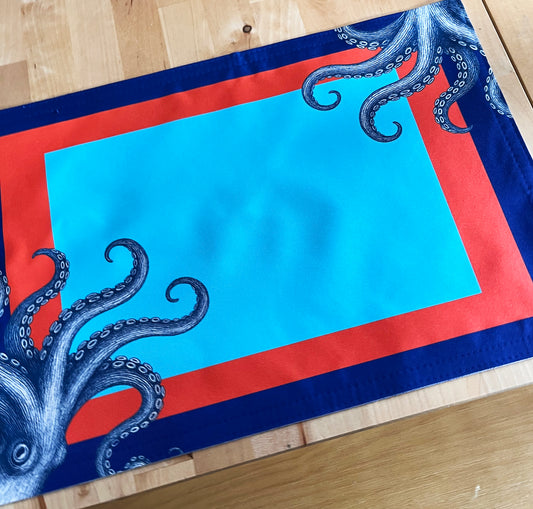 Placemat with blue octopus design on a red and blue border, with a detailed image.