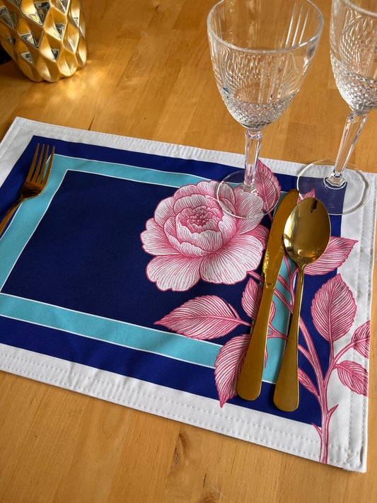 Floral placemat with cutlery and glasses on a wooden table; view of the placemat without a plate.