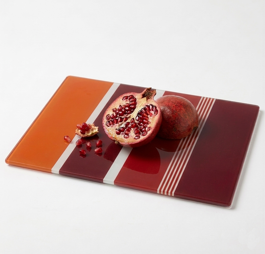 Glass cutting board with pomegranate on a white background