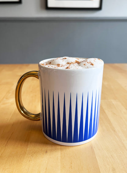 White mug with blue pattern on a wooden table, exclusive design.