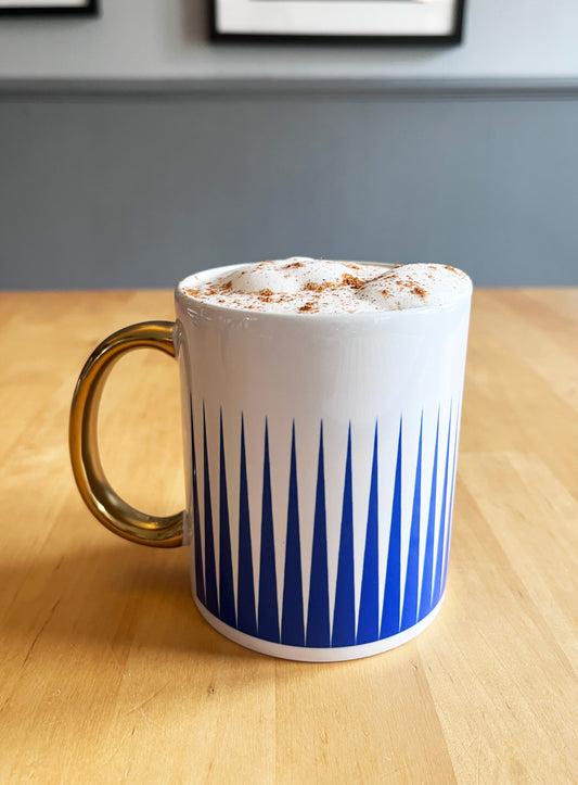 White mug with blue pattern on a wooden table, exclusive design.