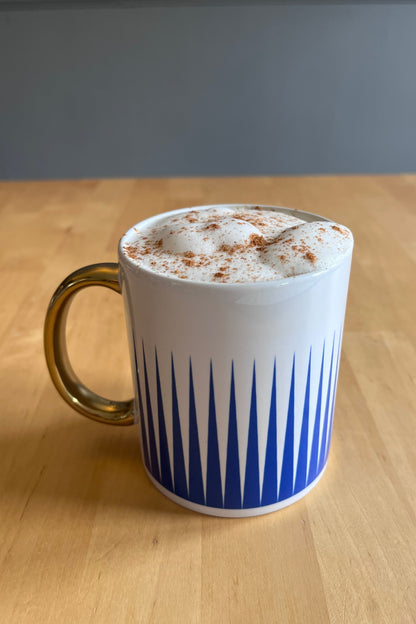 White mug with blue stripes on a wooden surface