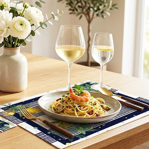 Dinner setting with pasta, wine glasses, and flowers on a table.