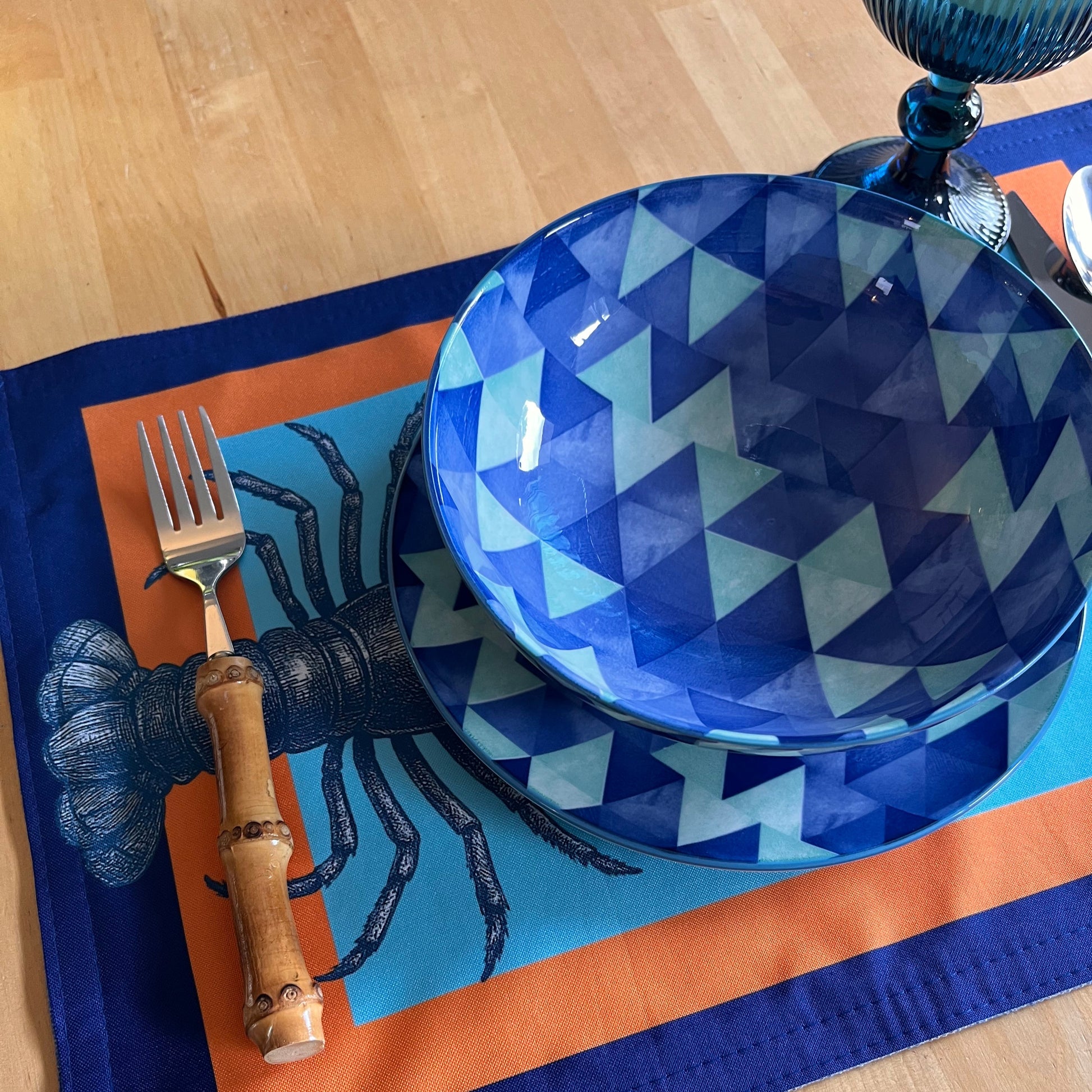 Blue geometric-patterned bowl with a fork on an orange and blue placemat.