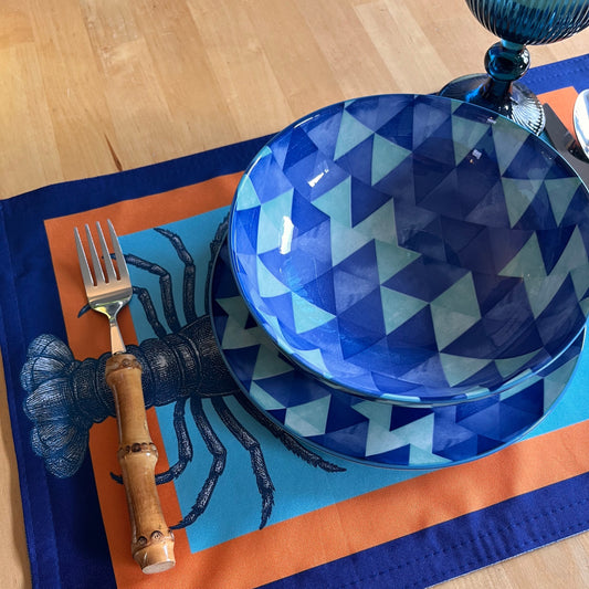 Blue geometric-patterned bowl with a fork on an orange and blue placemat.