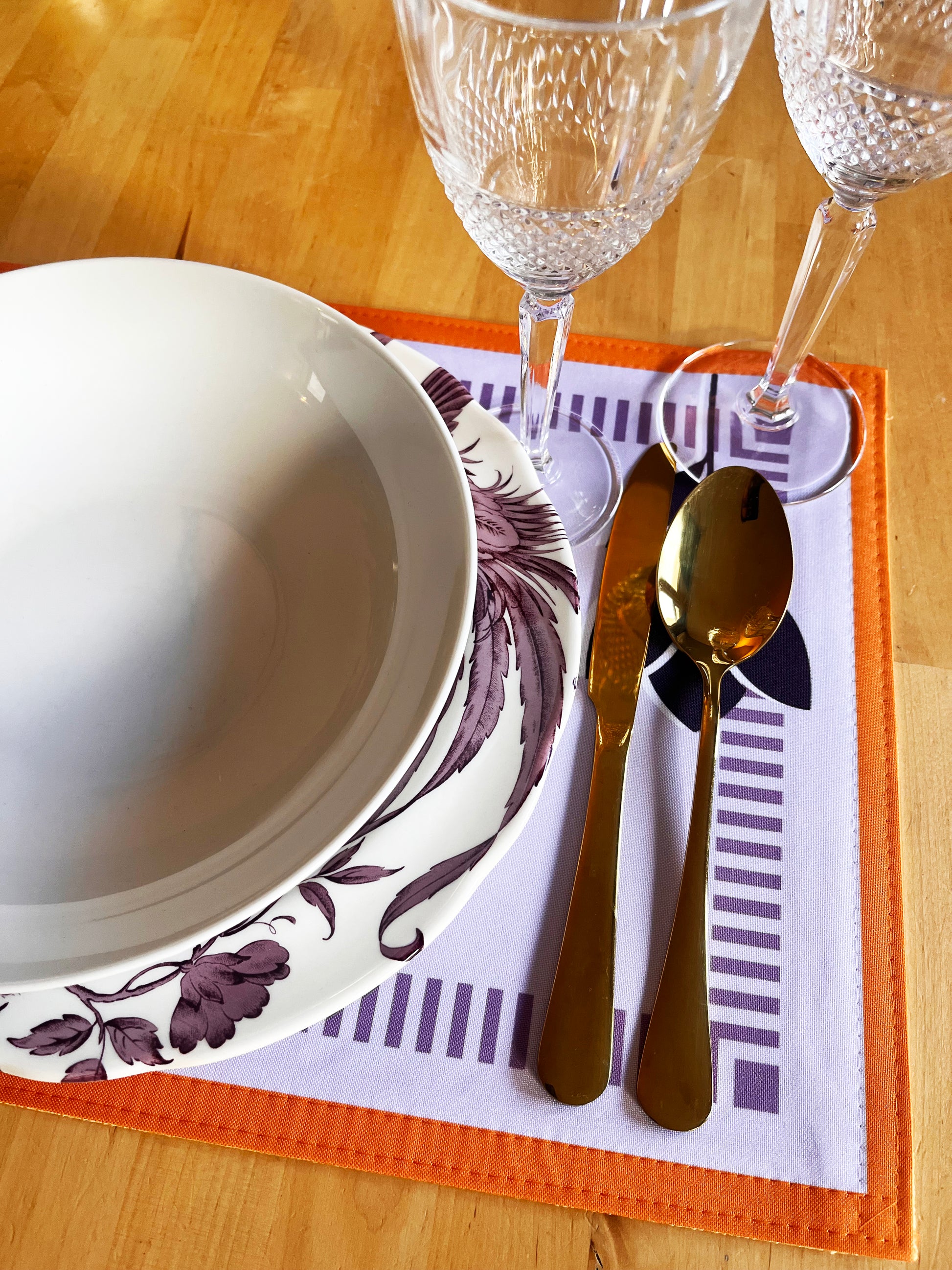 Dinner setting with a bowl, cutlery, and glasses on a placemat. Designed in the UK